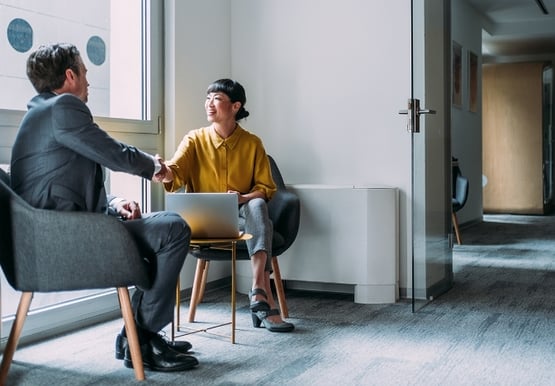 Two people shaking hands in a meeting